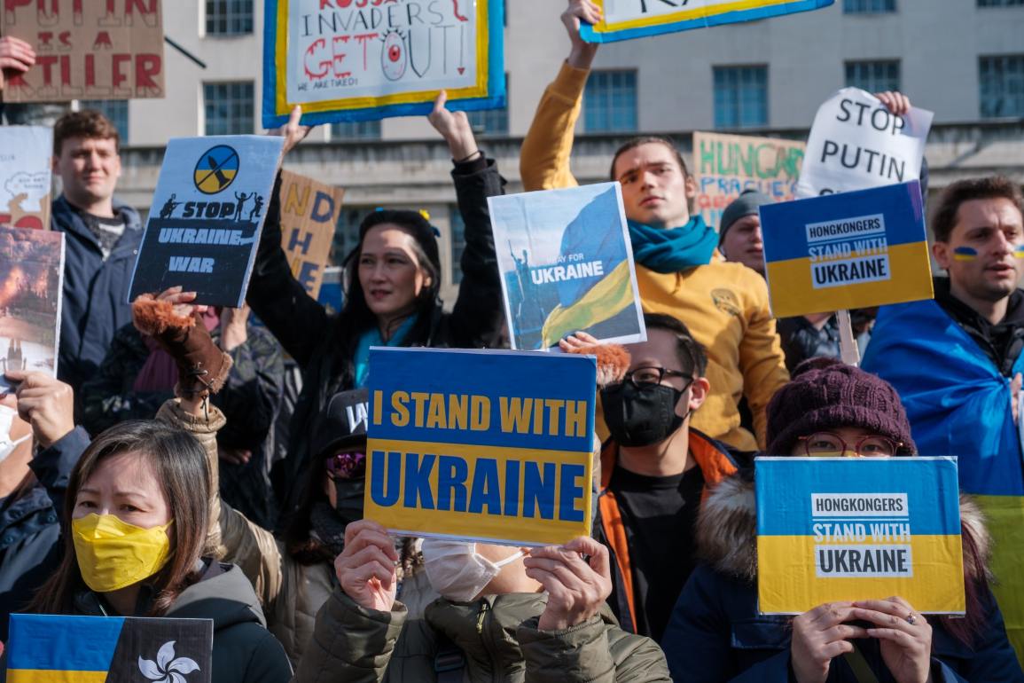 A crowd of demonstrators holding signs protesting against the Ukraine war.